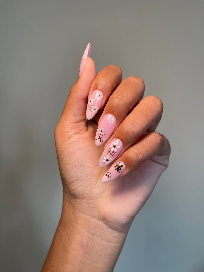 Hand with pink nail polish and Delicate stickers on a gray background