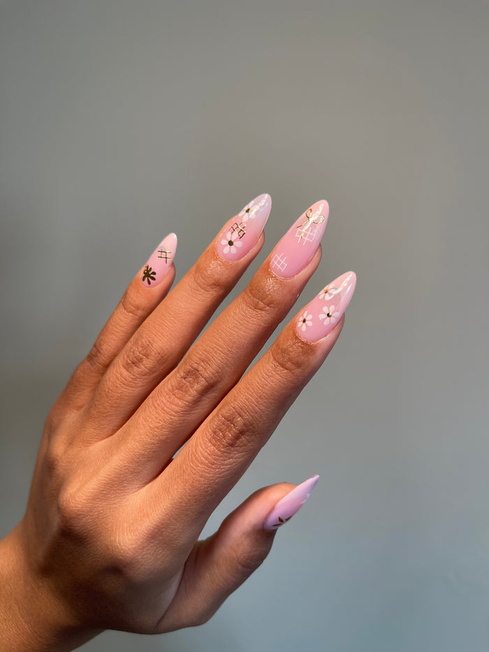 Hand with pink nail polish and Delicate stickers on a gray background