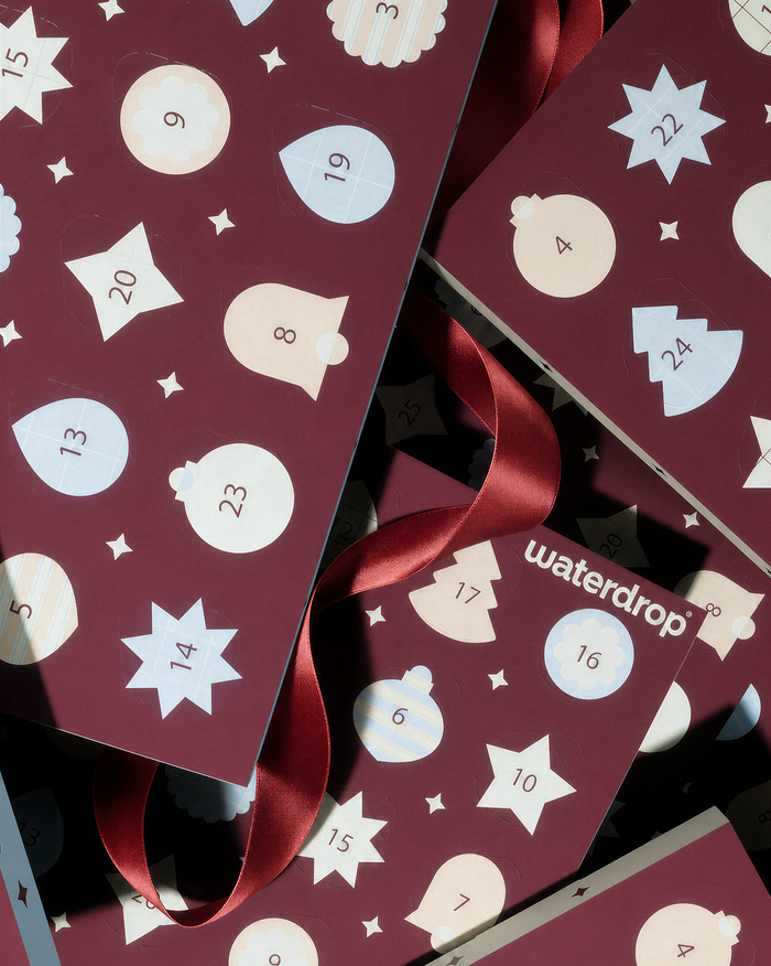 Adventní kalendář s čísly na vínově červených panelech a červenými stuhami.