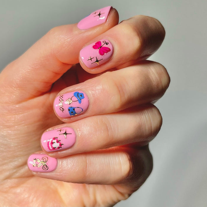 Hand with pink nail polish with nail art stickers on a neutral background