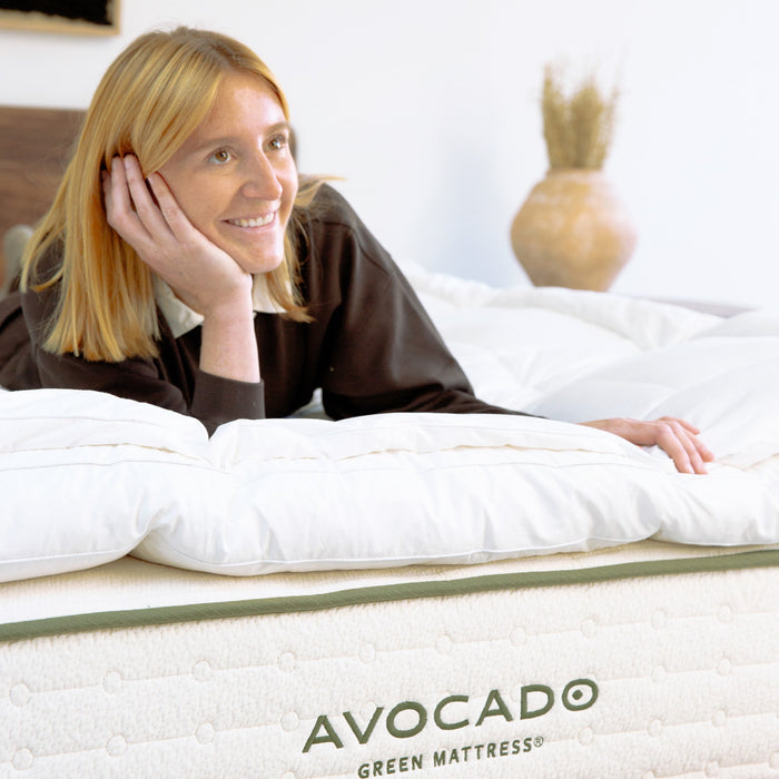 Woman lying on a plush Avocado Down Mattress Topper.