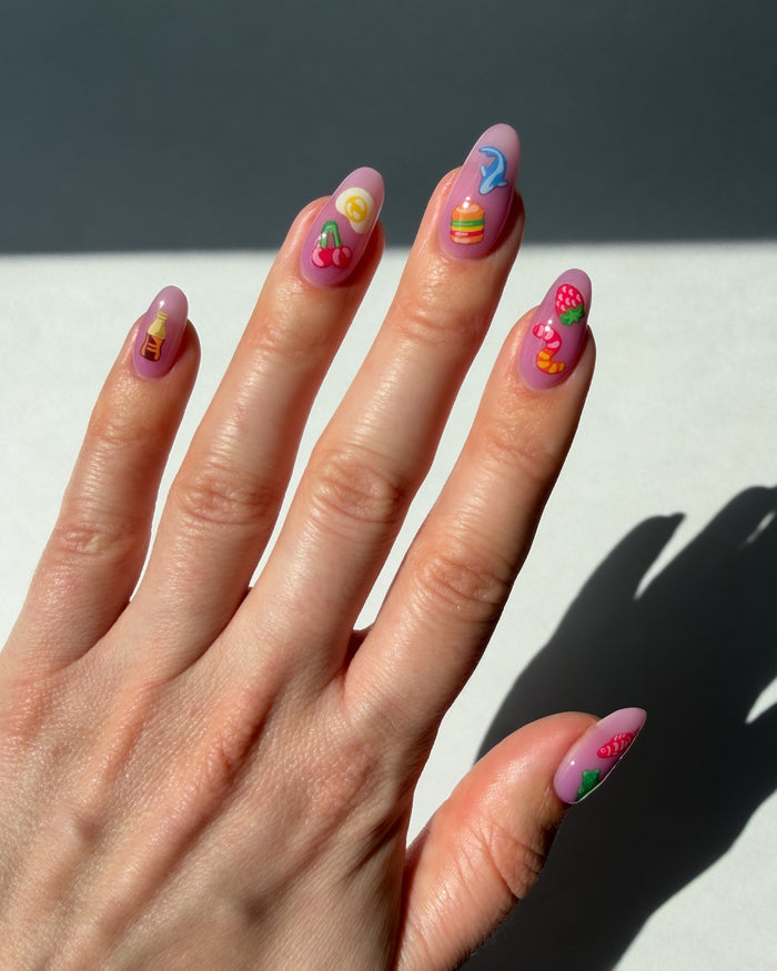 Hand with colorful nail art stickers on a neutral background