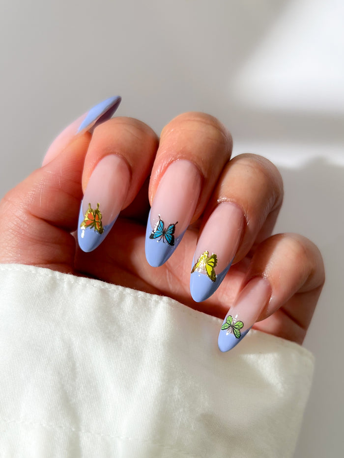 Nails with butterfly stickers on a light background