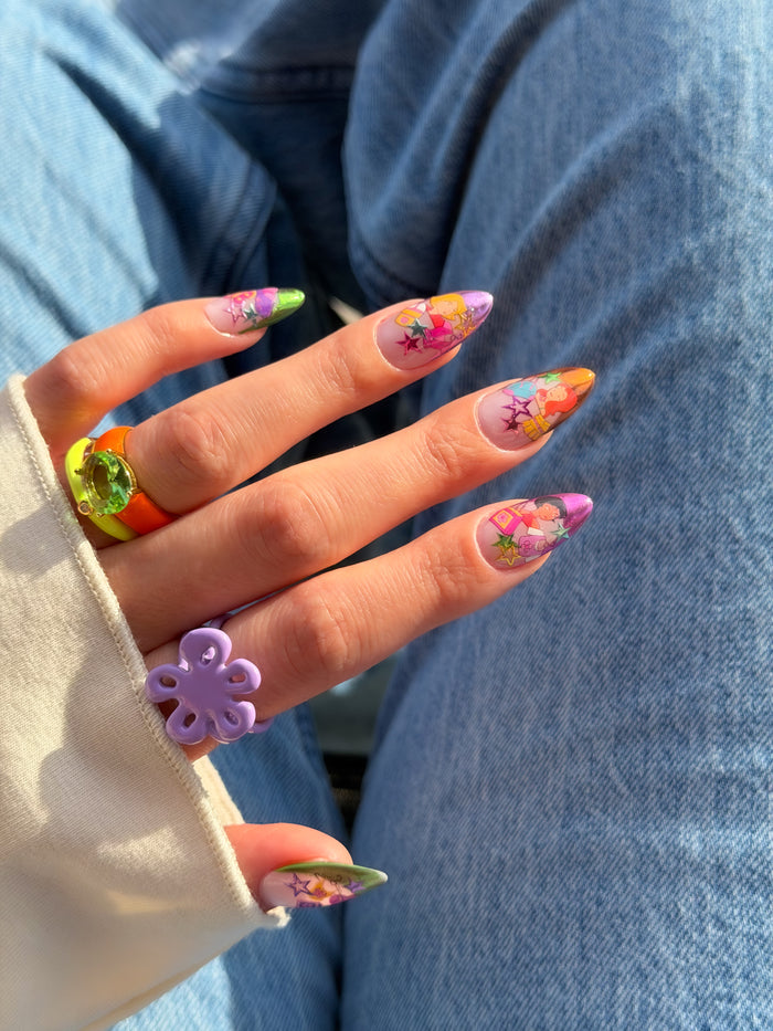 Hand with colorful floral nail art stickers on a denim background