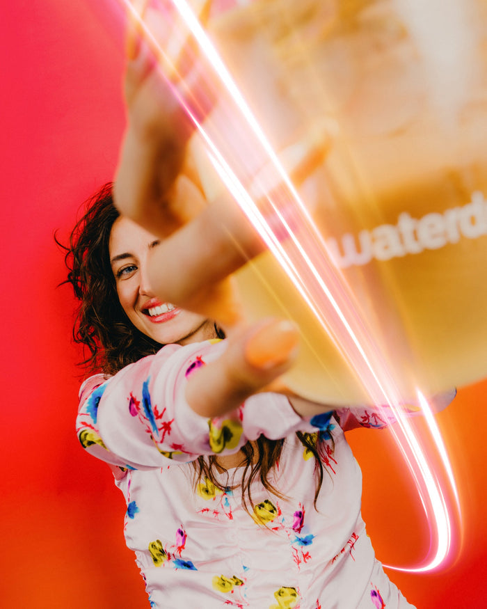 Woman holds Microenergy BOOST Twin Pack cup, smiling energetically.
