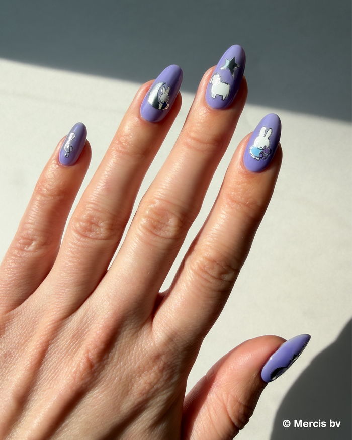Hand with purple nail polish featuring Miffy stickers on a neutral background