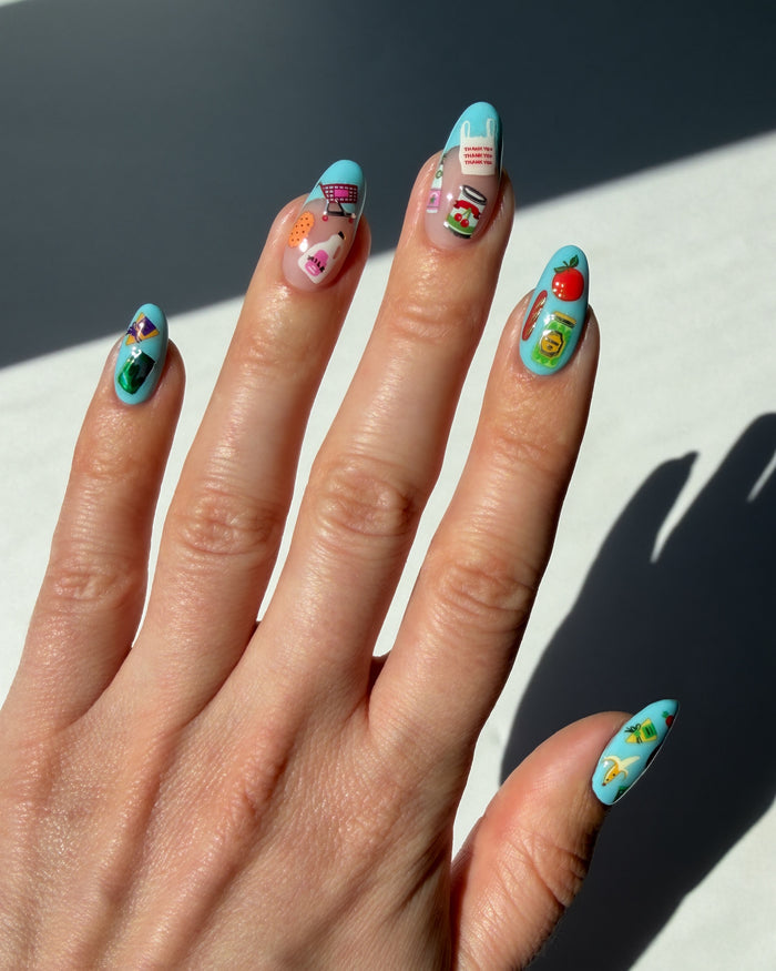 Hand with colorful nail art stickers on a light background
