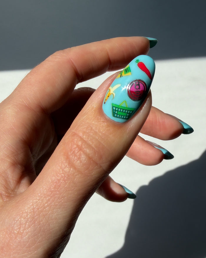 Nail with blue polish and colorful nail art stickers on neutral background