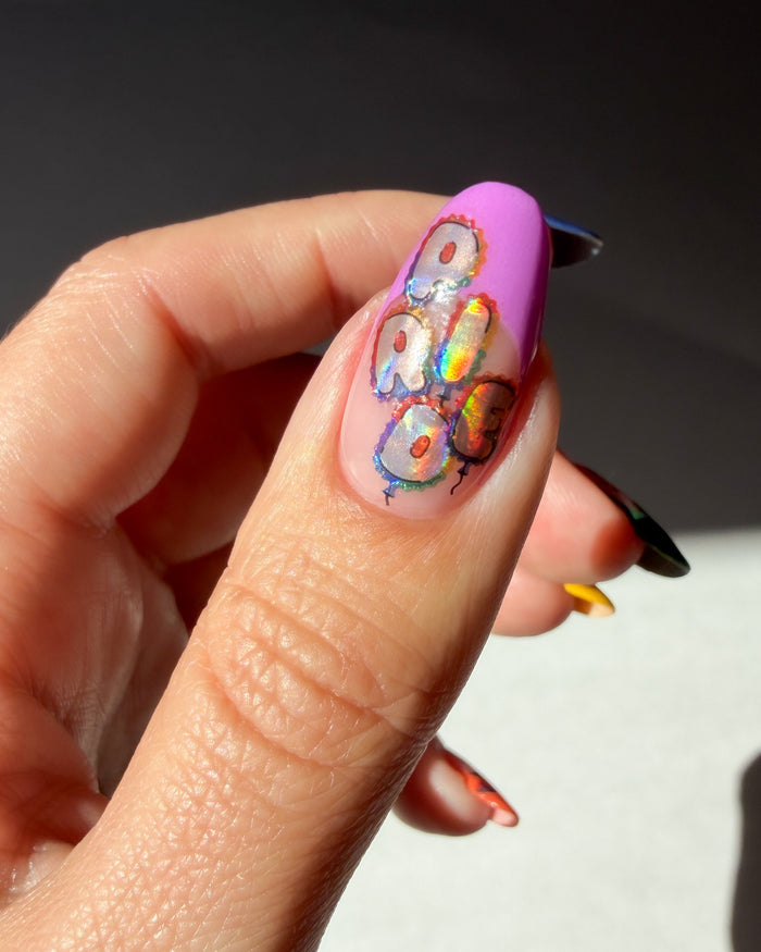 Close-up of a hand with a colorful nail design on a neutral background