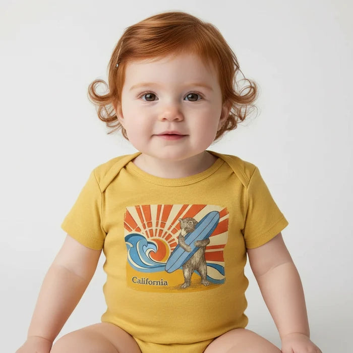 Yellow baby onesie with a bear holding a surfboard and sun design, labeled 'California'.