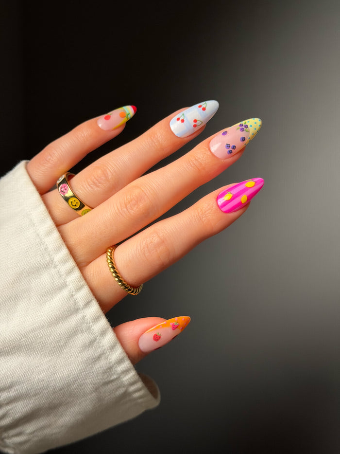 Hand with colorful nail polish and tiny fruit stickers