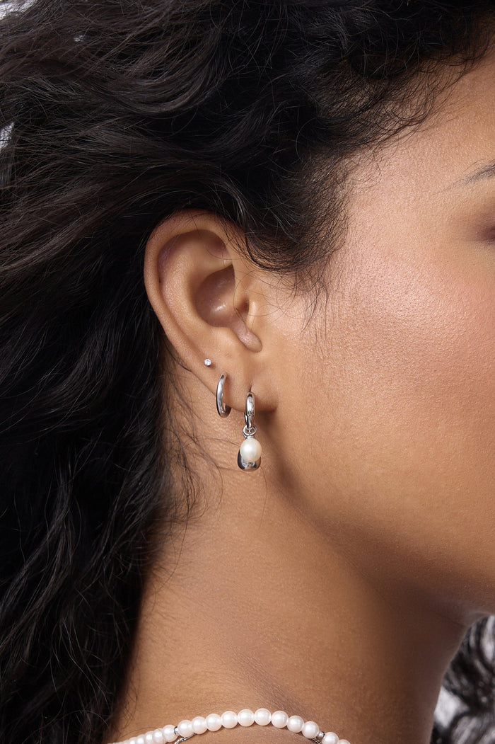 Woman wearing pearl earrings and a necklace with a neutral background