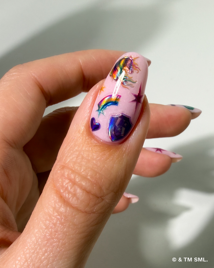 Nail with unicorn and rainbow design against a neutral background